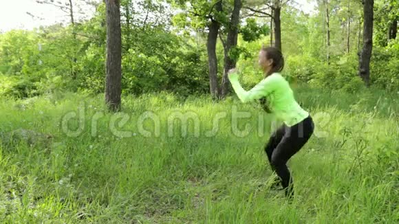 美丽的年轻女子蹲在大自然中锻炼视频的预览图