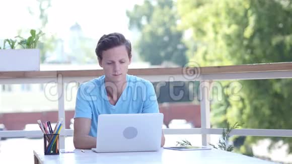 年轻设计师在他的笔记本电脑上工作户外视频的预览图