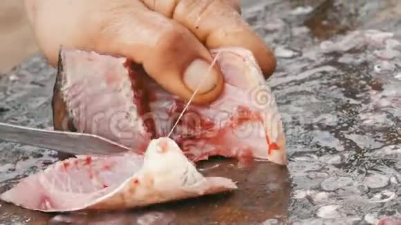 一个渔夫把一条活泼的大鱼切成碎片清洗淡水鱼以作进一步烹饪视频的预览图