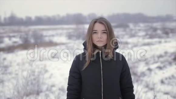 穿着黑色夹克的女孩在冬天的田野里视频的预览图