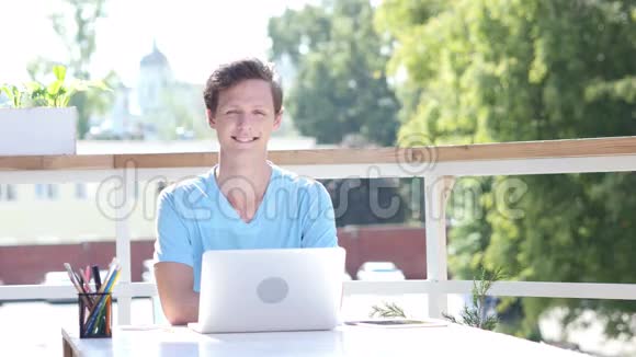 微笑自信的年轻人坐在办公桌前视频的预览图