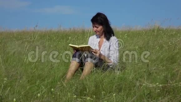 慢动作视频女性阅读书籍然后躺在草地上的绿色草坪上视频的预览图