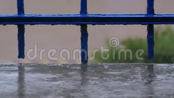 在下雨的街道背景下水滴滴在窗户阳台或栏杆上视频的预览图