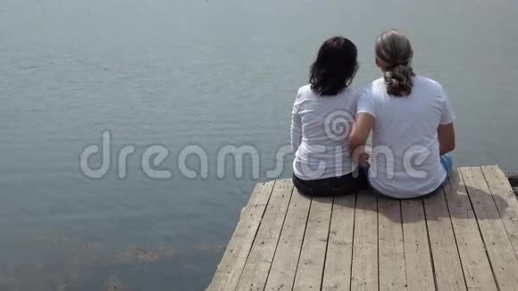 快乐男人拥抱坐在湖边的桌上的女人视频的预览图