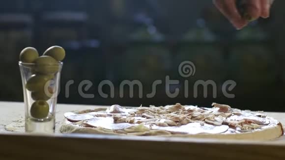年轻厨师在披萨上放橄榄视频的预览图