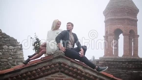 一对夫妇坐在老楼的屋顶上视频的预览图