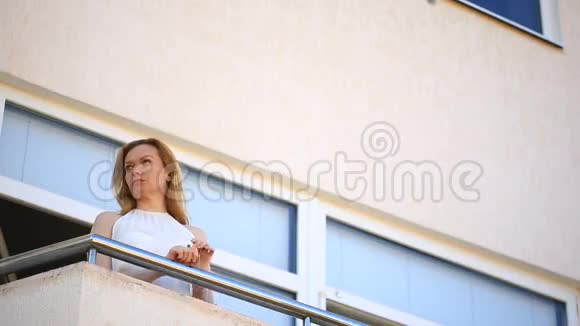 一个年轻的女人走到阳台上环顾四周她微笑着凝视着远方视频的预览图