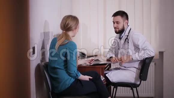 男性医生给年轻女性患者写一张处方并给她一些口头建议视频的预览图