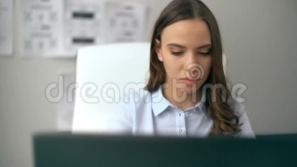 一位漂亮的女商人坐在办公室里用笔记本电脑工作视频的预览图