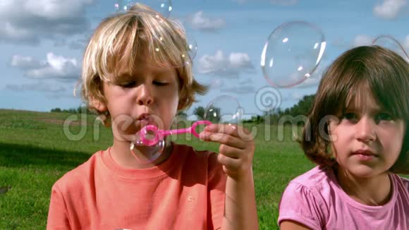 一个小男孩和一个正在拍摄电影的女孩一起吹泡泡视频的预览图