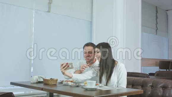快乐的年轻夫妇在餐厅用智能手机端着食物视频的预览图