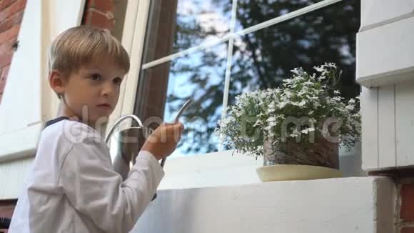 小男孩浇水可以在锅里开花女孩从窗户抬头看着他视频的预览图