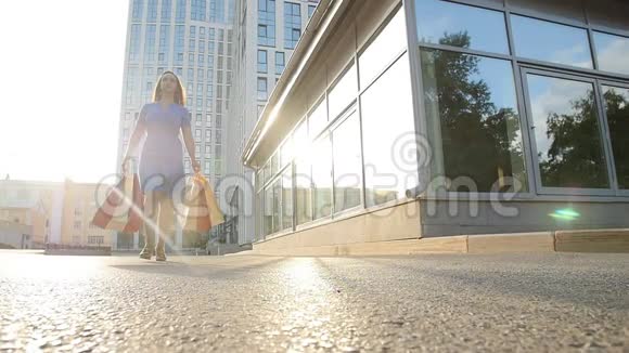 带着购物袋的年轻女子正沿街走着视频的预览图
