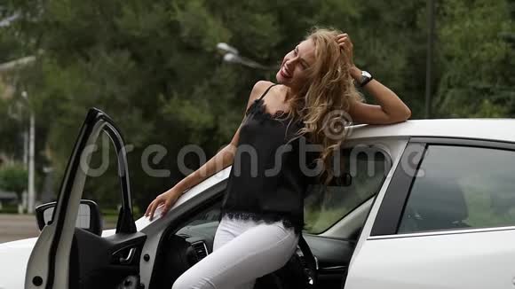 漂亮的金发女人靠近一扇敞开的车门女司机在摆姿势慢动作视频的预览图