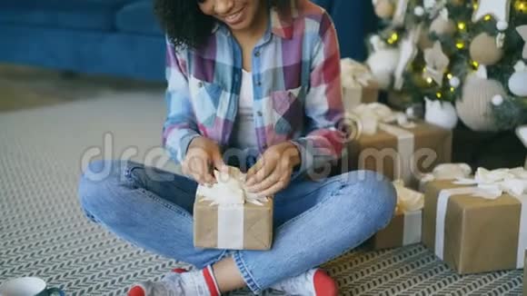 家中圣诞树旁漂亮的混血女孩包装盒视频的预览图