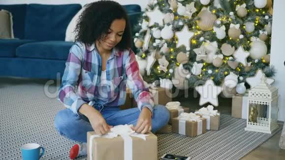家中圣诞树旁漂亮的混血女孩包装盒视频的预览图