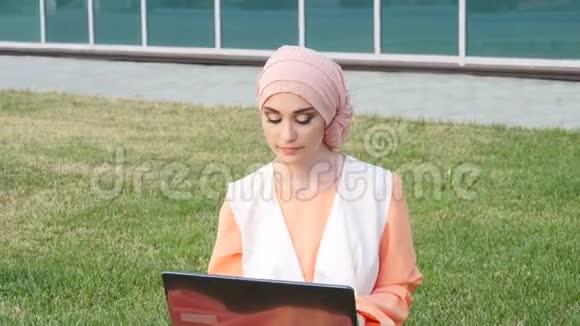 公园里漂亮的穆斯林女孩带着笔记本视频的预览图