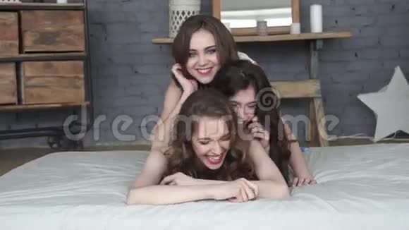 女朋友花时间在一起三个迷人的女孩躺在床上微笑慢动作视频的预览图