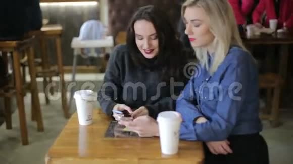 女孩在咖啡店用智能手机观看照片视频的预览图