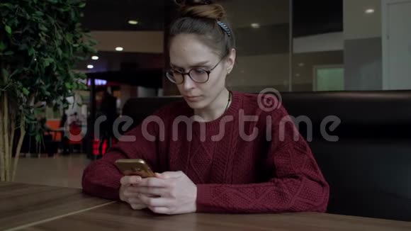 可爱的女性在咖啡馆里使用智能手机视频的预览图