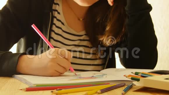 年轻的女人拿着铅笔在家画画为成人和儿童着色为了缓解压力成人着色书视频的预览图