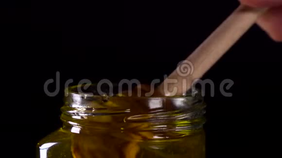 有机蜜滴在黑色背景上的木制蜂蜜勺子上视频的预览图