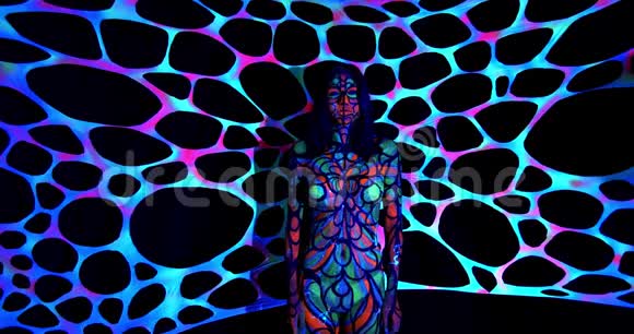 有紫外线身体艺术的年轻女子站在黑暗中发光4K视频的预览图