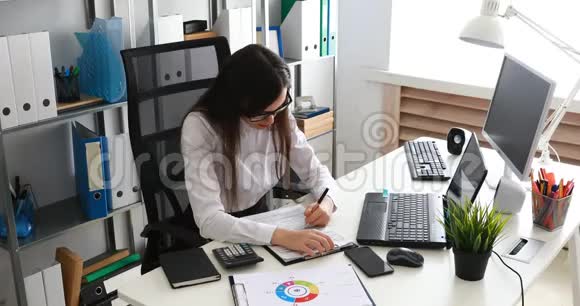 女商人在现代办公室里填写文件和使用笔记本电脑视频的预览图