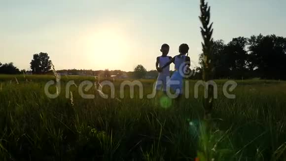 剪影儿童的身影男孩和女孩跳跃玩得开心在太阳的背景下在日落时跳舞视频的预览图