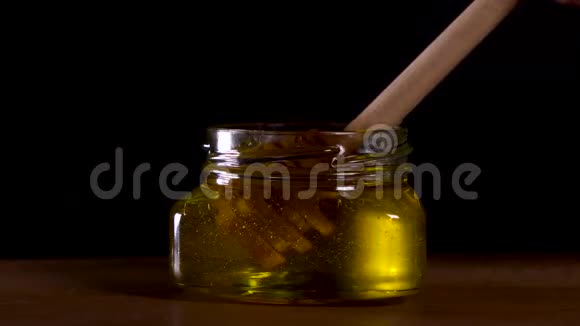 有机蜜滴在黑色背景上的木制蜂蜜勺子上视频的预览图