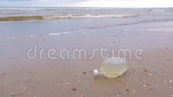 塑料瓶被带到沙滩上的岸边视频的预览图