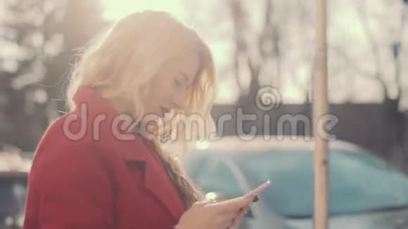 穿红色外套的商务女性在阳光城市使用手机稳住摄像机视频的预览图