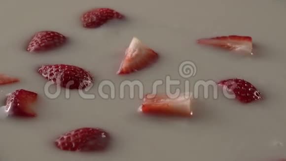 在慢速运动桌面上用白色奶油液体旋转草莓视频的预览图