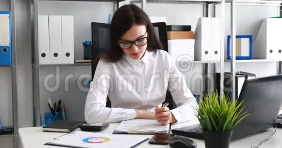 女商人在现代办公室里填写文件和使用笔记本电脑视频的预览图