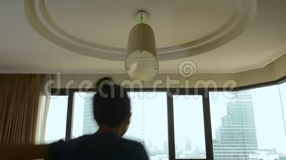 幸福的家庭女人男人和两个孩子带着一个手提箱在摩天大楼的背景下在一个全景窗里视频的预览图