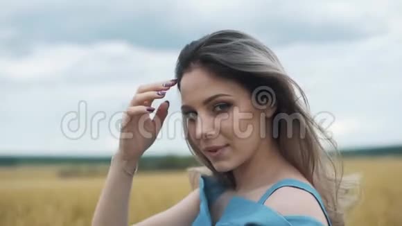 一个穿着蓝色衣服的年轻女孩站在田野里风吹动她的头发视频的预览图