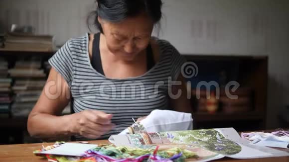 老年妇女在白棉布上缝制十字绣图片4K慢动作视频的预览图