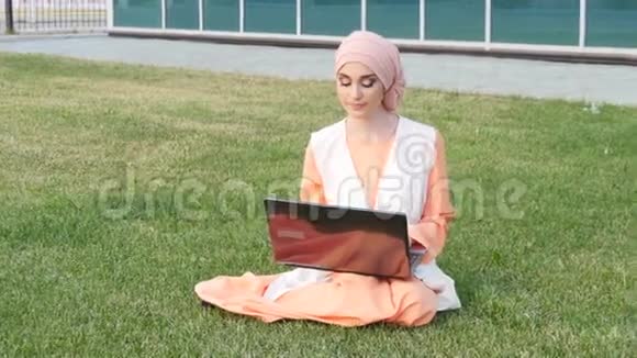 公园里漂亮的穆斯林女孩带着笔记本视频的预览图