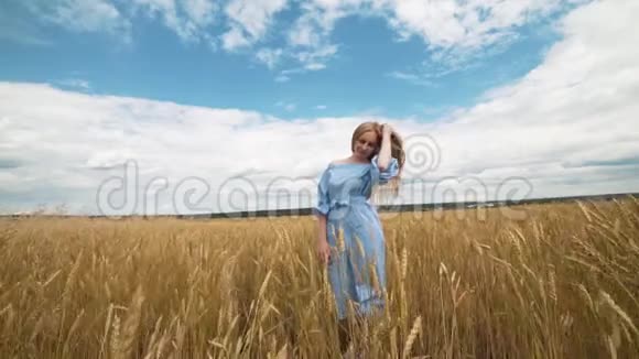 一个穿着蓝色衣服的年轻女孩站在田野里风吹动她的头发视频的预览图