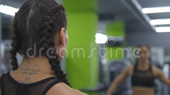 年轻漂亮的女人在健身房训练在镜子前举起和放下哑铃体育健身女孩视频的预览图
