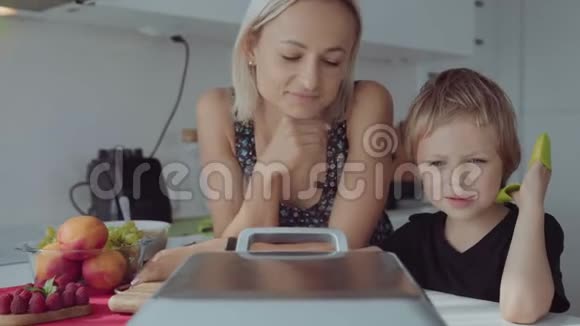 小女人在厨房里做华夫饼可爱的男孩帮她视频的预览图