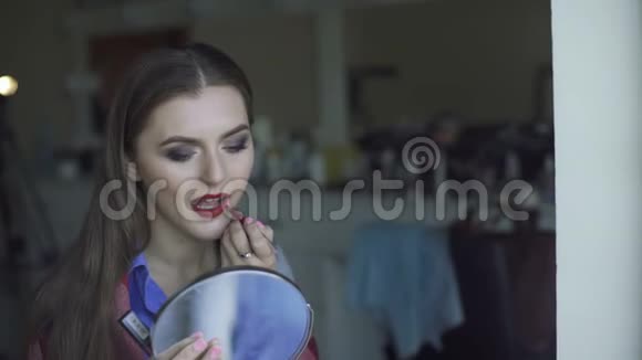 年轻漂亮的女人在镜子前涂口红视频的预览图