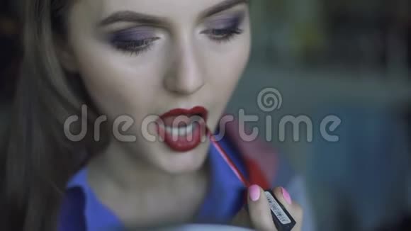 年轻漂亮的女人在镜子前涂口红视频的预览图