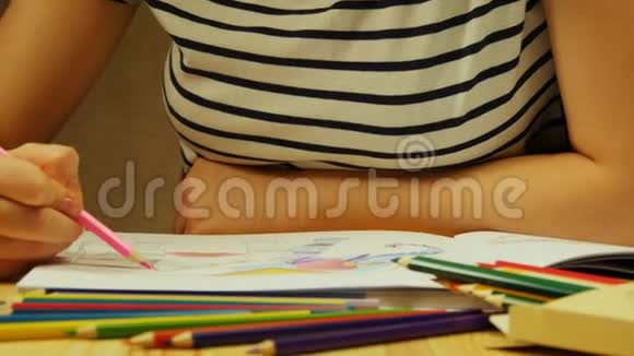 年轻的女人拿着铅笔在家画画为成人和儿童着色为了缓解压力成人着色书视频的预览图