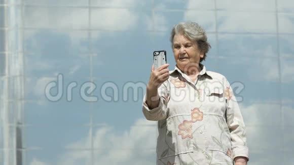 老年妇女使用银色智能手机拍照视频的预览图