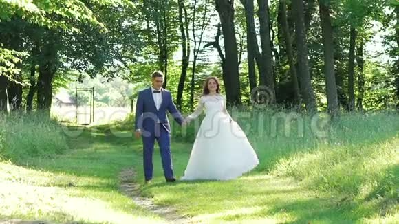 微笑的新娘对她英俊的新郎摆姿势散步和亲吻慢慢地视频的预览图