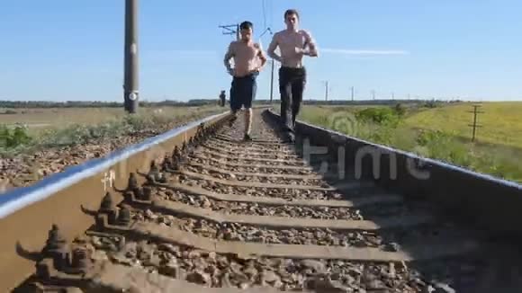 两个人在铁轨上的铁轨之间奔跑在铁路轨枕上慢跑的跑步者运动腿视频的预览图