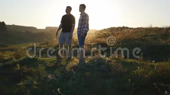 日落时分父亲和儿子在户外谈话的肖像两个成年男子站在山上的绿草上视频的预览图