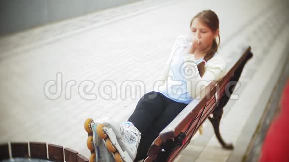 一个小胖女孩在滚筒上喝水一个孩子在长凳上的公园里喝水视频的预览图