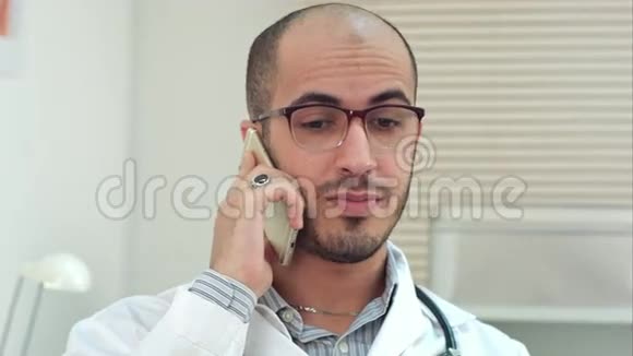 戴眼镜的年轻男医生在用手机说话视频的预览图